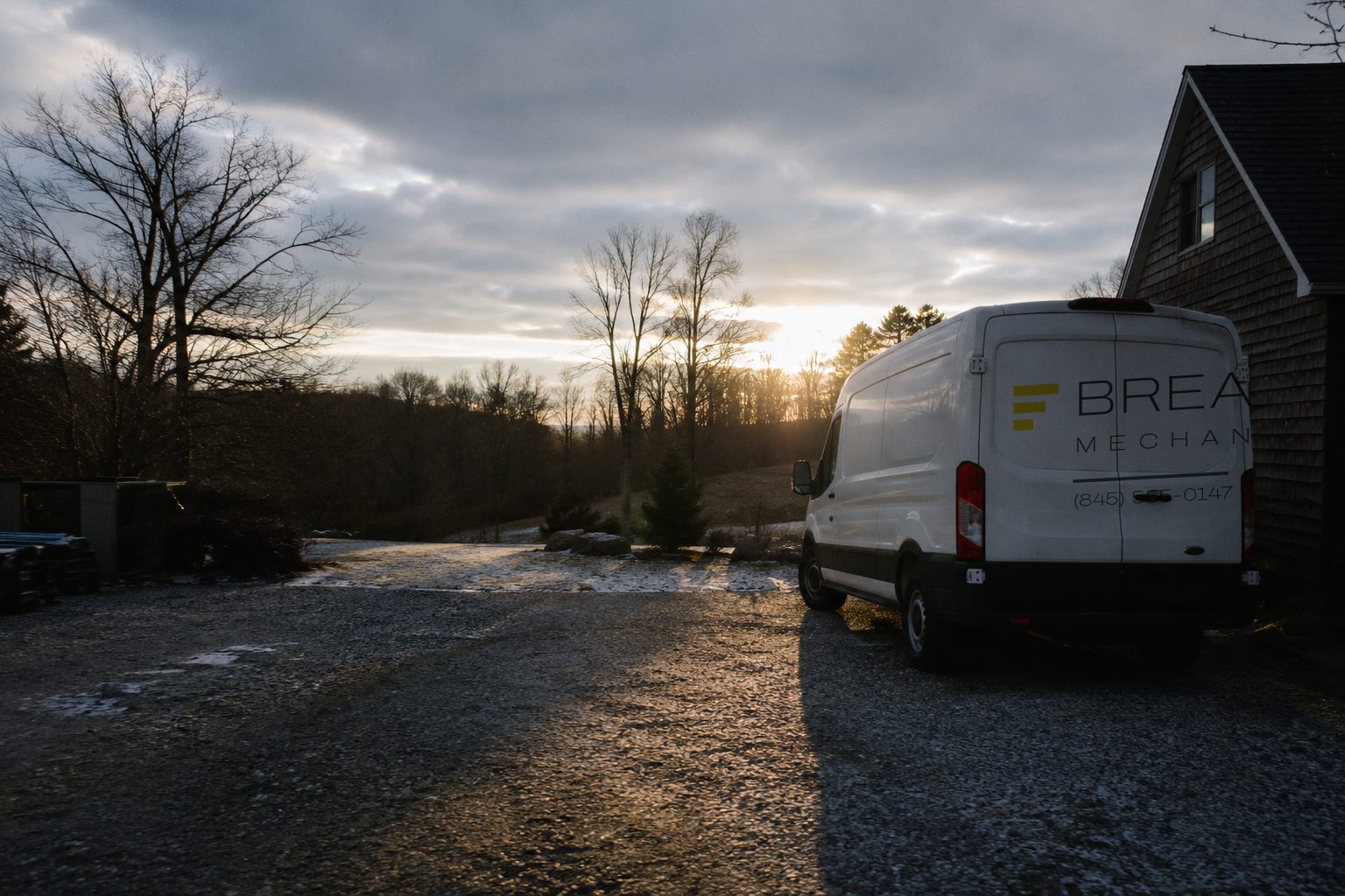 A white Breakneck Mechanical service van backed into a gravel driveway in Cold Spring, New York at first light on a February morning.